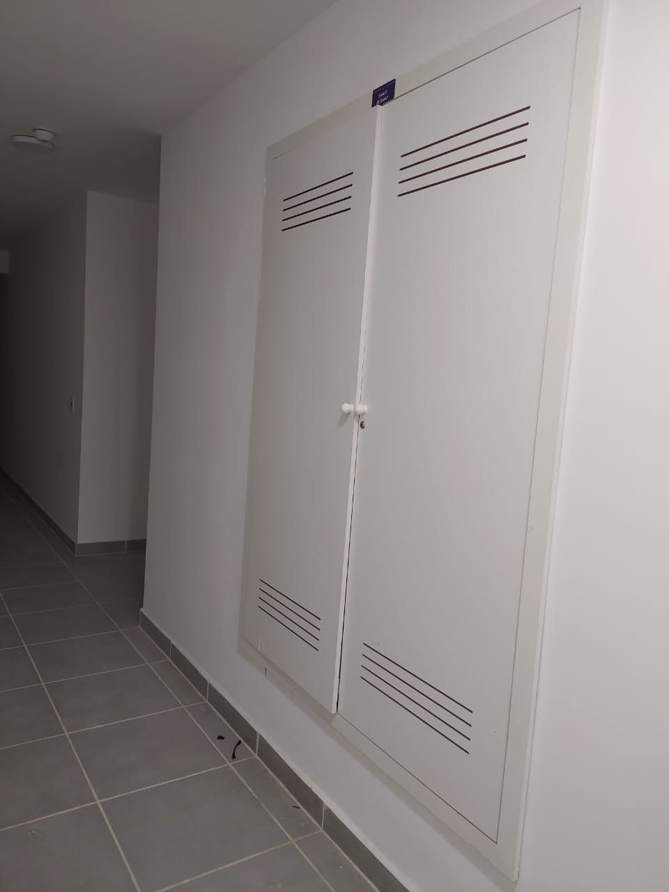 Porta shaft branca dupla com venezianas instalada em corredor